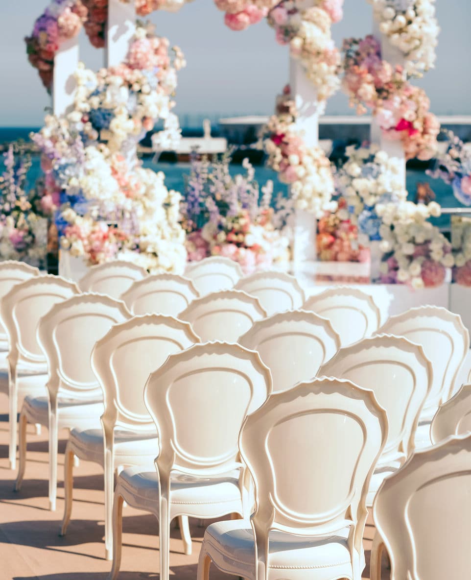 Sillas y arco floral montados para una ceremonia frente al mar