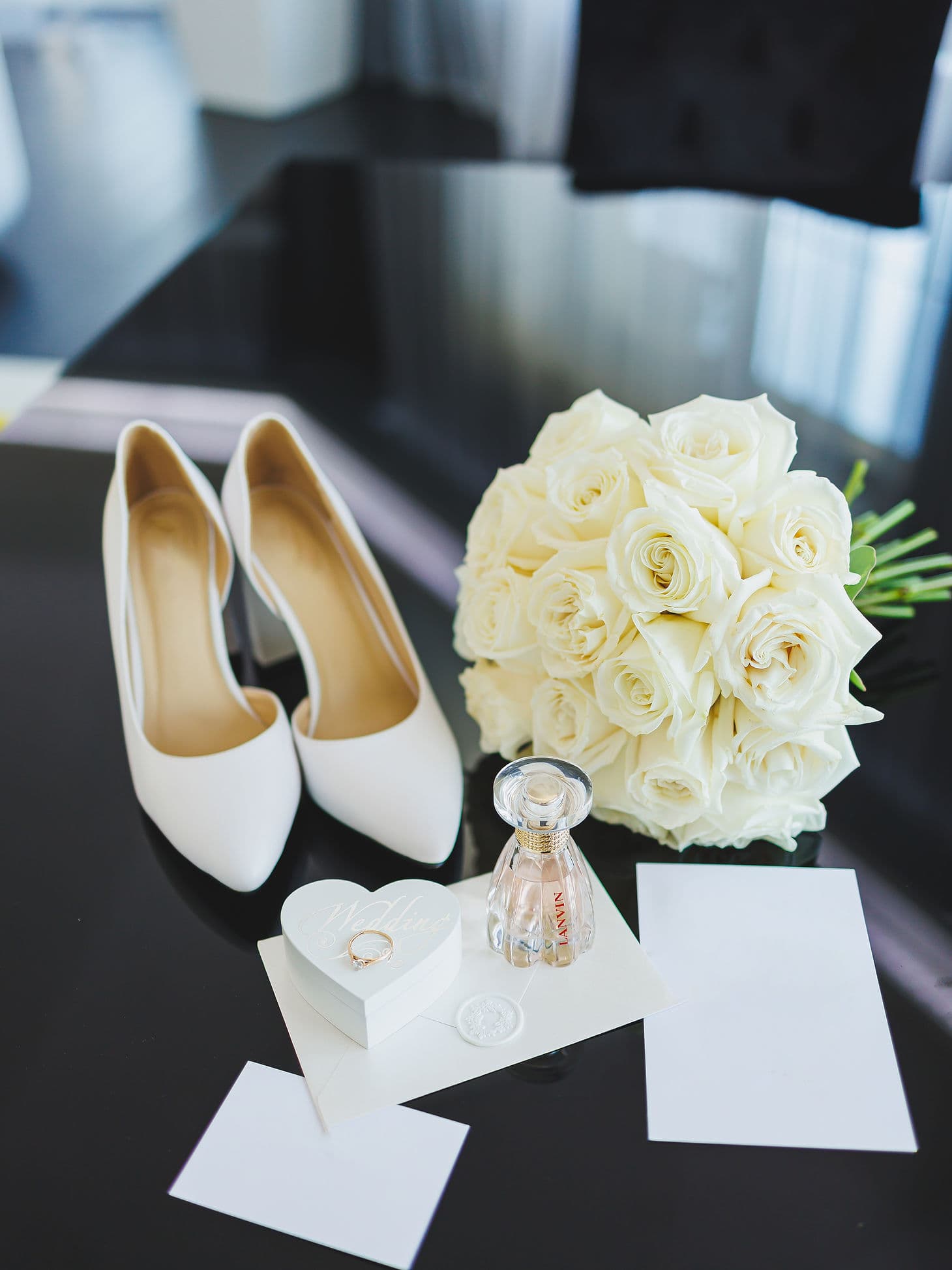 Zapatos de novia junto a un ramo de rosas blancas